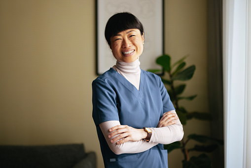 Happy Japanese female doctor standing with crossed arms and looking at camera.