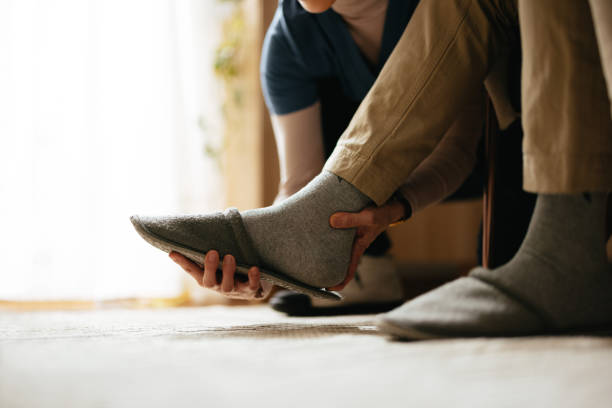 istock Anonymous Woman Helping To Take off a Slipper From an Unrecognizable Man’s Foot 2087259327