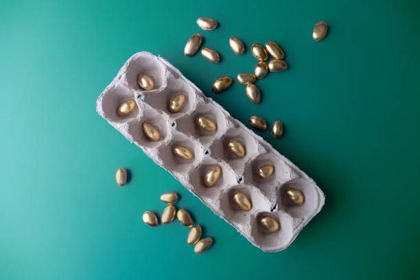Metaphor for monthly: savings, investing, diversification, growth, budgeting, debt management, financial goals and planning, wealth, paying monthly bills, retirement, opportunity - using gold foil eggs and 12 pack egg carton