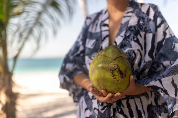 istock Unrecognizable female tourist holding pummelo fruit while standing on the beach 2087365840