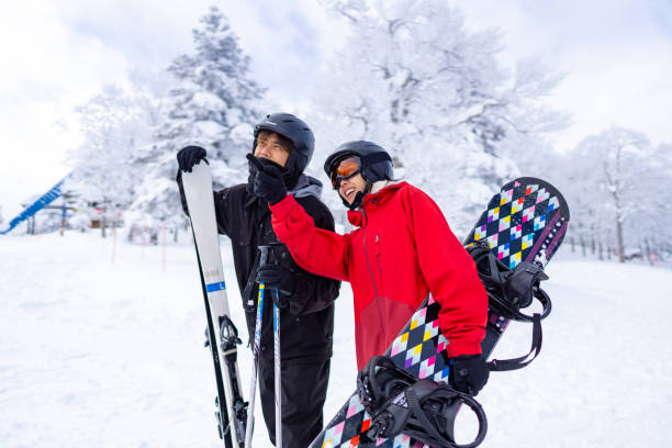 Asian couple practicing snowboard and ski together at snowy mountain on winter vacation Asian man and woman practice freeriding snowboard and ski on snowy mountain at ski resort. People enjoy outdoor active lifestyle travel nature and winter extreme sport training on holiday vacation. japanese snowboarder stock pictures, royalty-free photos & images
