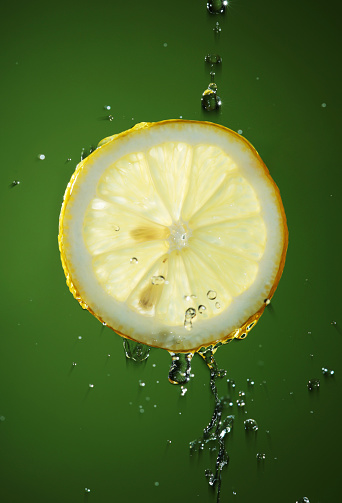 A broad stream of water flows from the lemon on a black background
