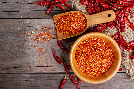Dried chilies with chili powder, pepper, and red paprika in a wooden bowl Spicy seasoning Healthy food, top view