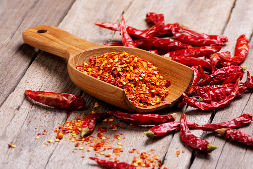 Chili powder in a wooden spoon, dried chili peppers and red paprika, spicy, healthy food, top view