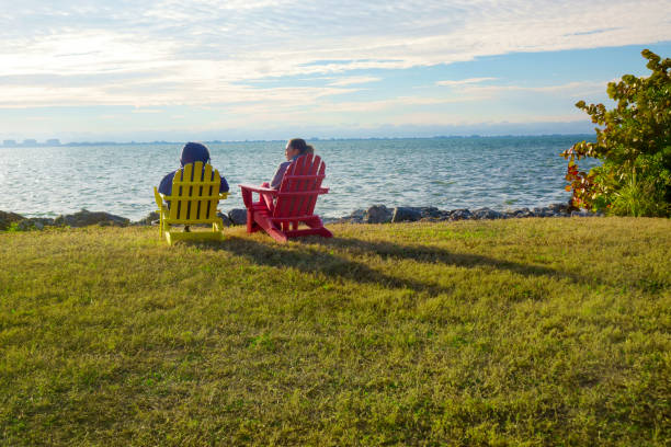 Rear view of two women sitting on Adirondack Chairs and watching view in Florida