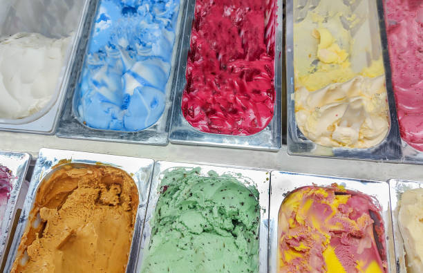 Big range of ice cream of various varieties and colors in metal containers on shop window