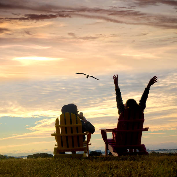 Rear view of two women sitting on Adirondack Chairs and watching view in Florida