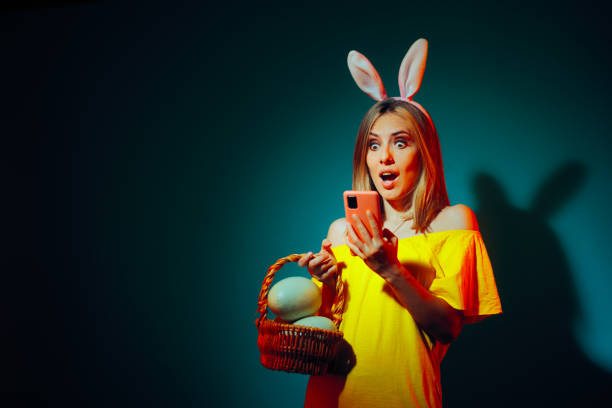 Funny Easter Woman Reading a Surprising SMS Text Excited Girl receiving a chat message on paschal holidays unusual basket stock pictures, royalty-free photos & images