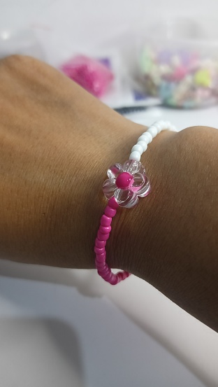 woman's hand wearing a pink and white beaded bracelet.