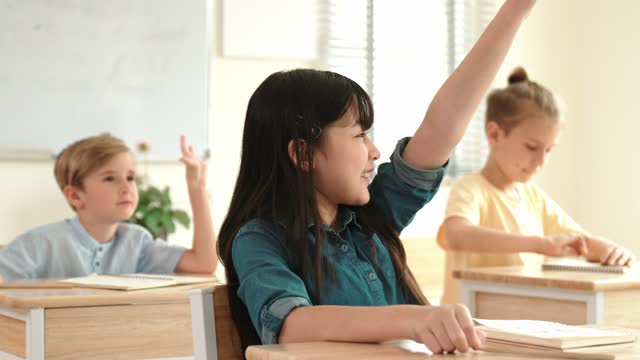 Happy girl raising hand for asking and answering teacher at classroom. Pedagogy.
