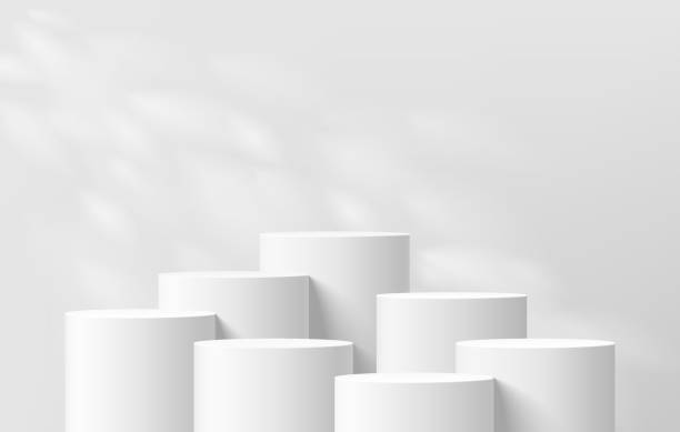 istock 3D background with set of realistic white cylinder podium pedestal and natural leaf light scene. Abstract composition in minimal design. Platforms mockup product display presentation. Stage showcase. 2087836579