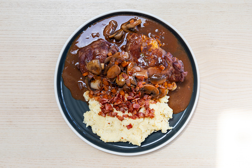 A plate of coq au vin with mashed potato.