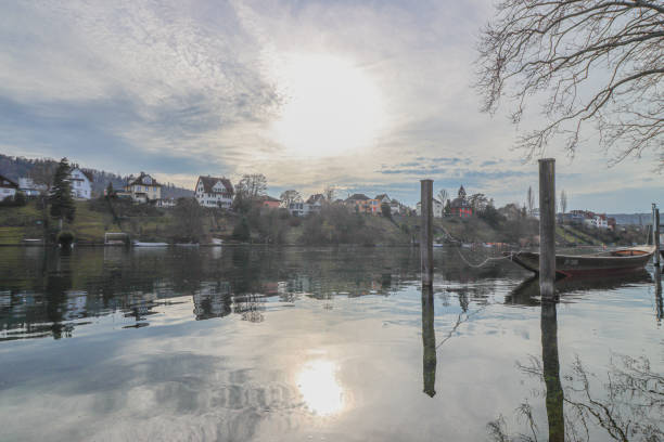 Two red canoes paddle along the Neckar River in Heidelberg, Germany, during a vibrant sunset. The scene is framed by historic riverside houses and lush green hills.