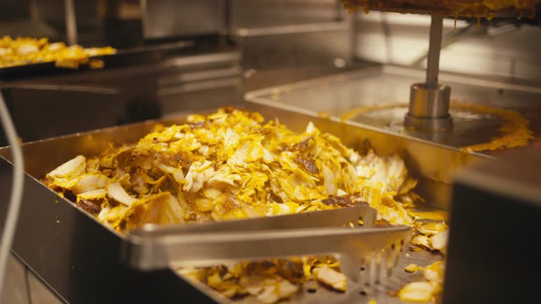 Golden kebab meat slicing at a shop, close-up view, warm lighting