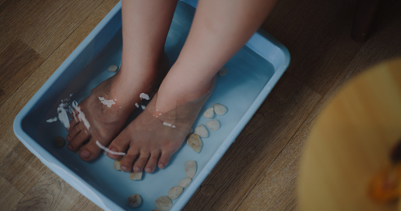High angle view,  Feet of Young woman in tub and massage with small rocks doing foot therapy in appropriate temperature water in wellness spa resort