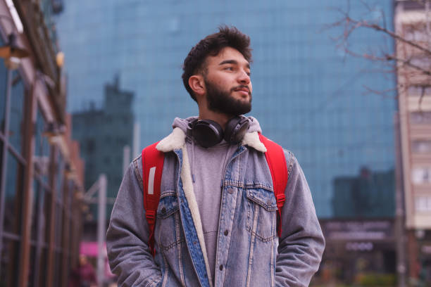 Young man, hands in pocket, walking in the city