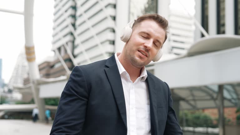 Happy business man using headphone listening relax music and move along. Urbane.