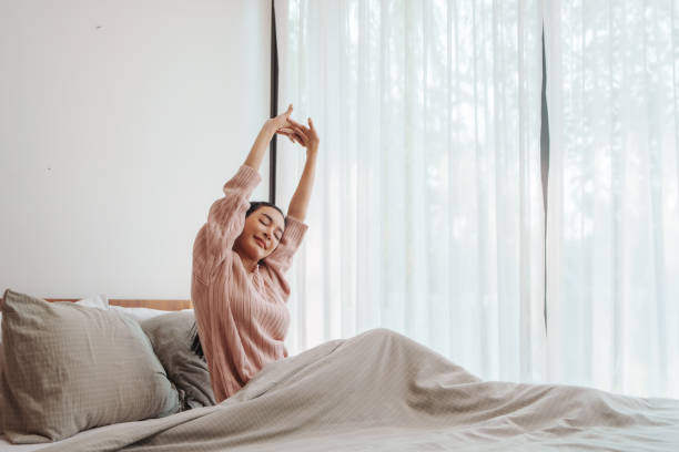 Woman stretching in a sunny bedroom.