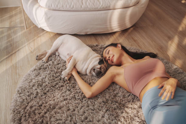 Young woman lying beside her dog on a rug, relaxed and content