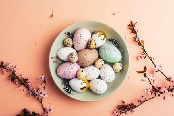 istock Easter eggs on green plate on light peach background with cherry blossom branches. Top view, flat lay 2088190145