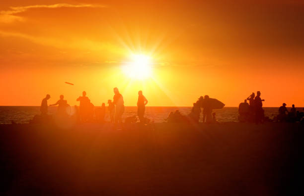 istock Silhouetted people enjoy beach holiday during sunset 2088192256