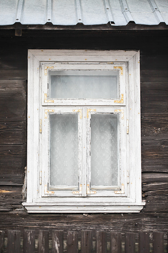 Wall of grey stone building with windows and rolling shutters