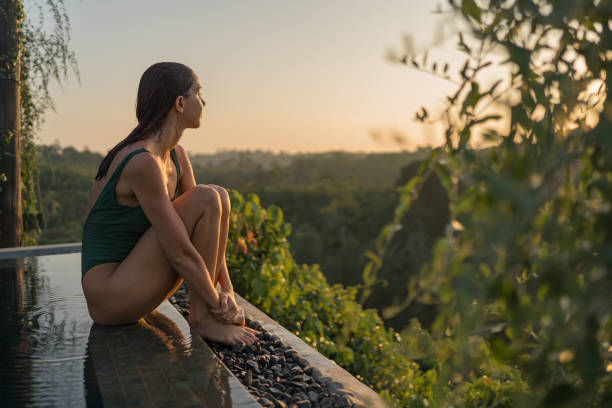 istock Young woman relaxes on edge of swimming pool 2088198223