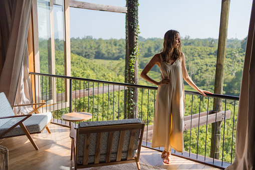 Young woman relaxes on verandah above tropical rainforest