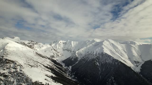 Snow-capped Fagaras Mountains under a clear blue sky, panoramic aerial shot
