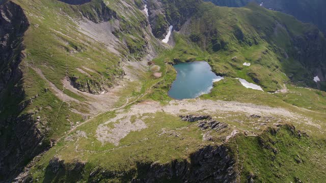 Serene aerial view of Capra Lake nestled in the lush Fagaras Mountains, Romania, under clear skies