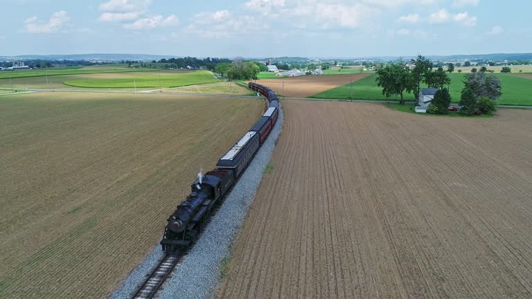 An Aerial View of an Approaching Steam Passenger Train, Blowing Smoke and Steam on a Partially Sunny Day