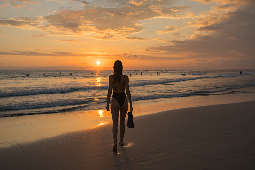 Young woman wades in sea shallows in sunset light