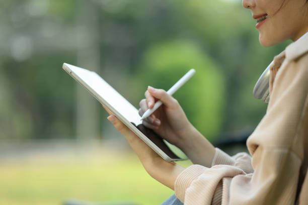 istock Cropped shot smiling female student using digital tablet, doing homework in the public park 2088220156