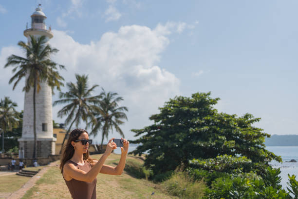 istock Young woman takes photo below lighthouse 2088220181