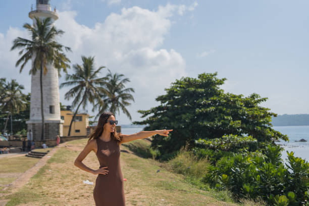 Young woman explores headland under lighthouse