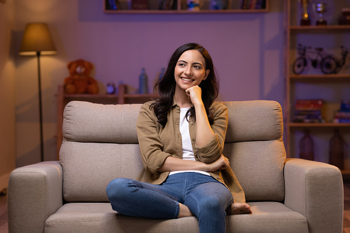 Young woman relaxing while sitting on comfortable couch in living room