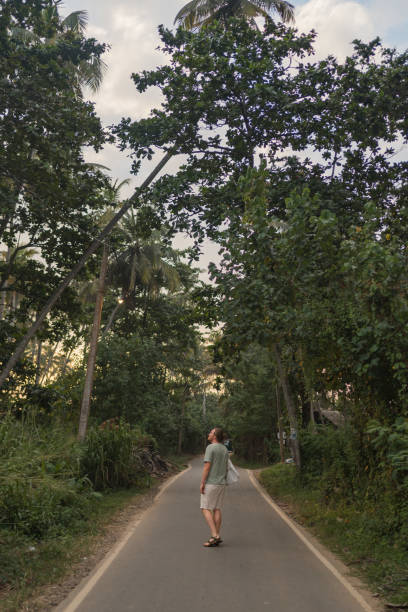 istock Man walks down rural road in rainforest 2088225470