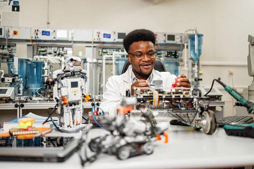 African American engineer examining AI robot