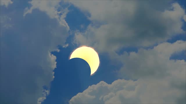 Total solar eclipse with heap white cloud blue sky look like shape heart time lapse