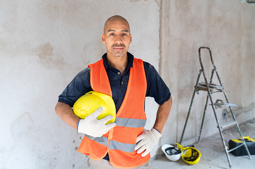 Portrait of a professional construction worker with safety gear against the backdrop of a renovation site.