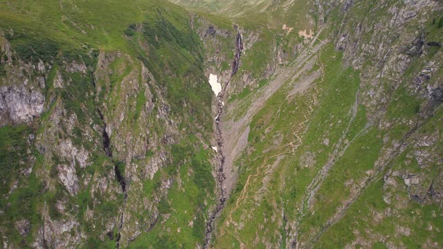 Valea rea in the fagaras mountains with rugged terrain and trails, during daylight, aerial view