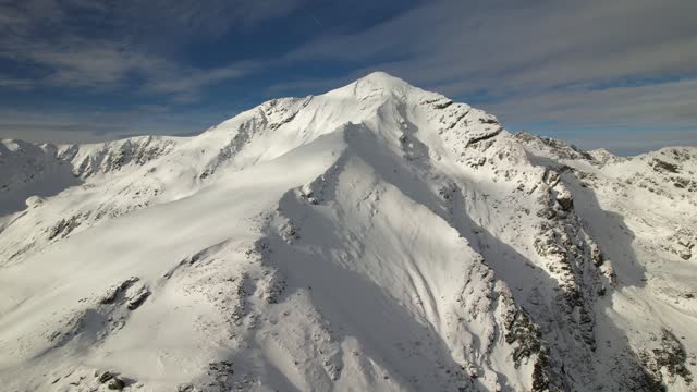 Lespezi peak in fagaras mountains under a clear blue sky, snowy landscape, aerial view