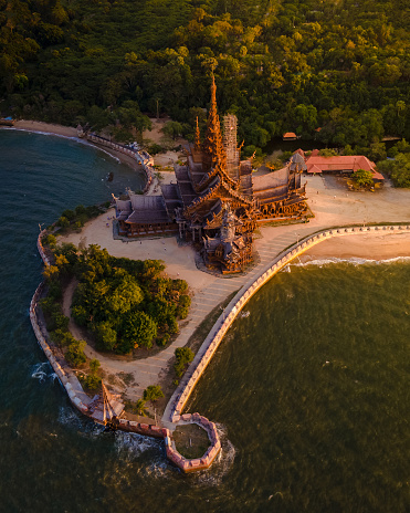 The Sanctuary of Truth wooden temple in Pattaya Thailand at sunset seen from the beach by the ocean, drone aerial view at Pattaya skyline