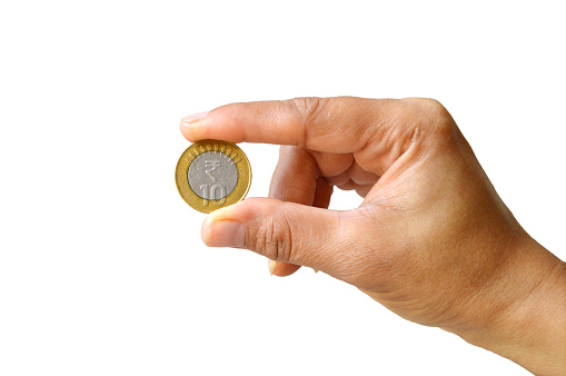Cutout one hand holding and displaying or showing a ten 10 rupee denomination coin in Indian currency money in gold and silver color isolated over white colored transparent background with copy space