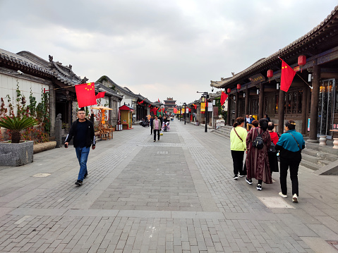 Tourists walking on a pedestrian street decorated with chinese flags in Datong old town, Shanxi province.