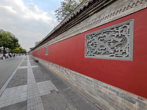 People in the background walking on the sidewalk by an old wall in Datong ancient town, Shanxi province.