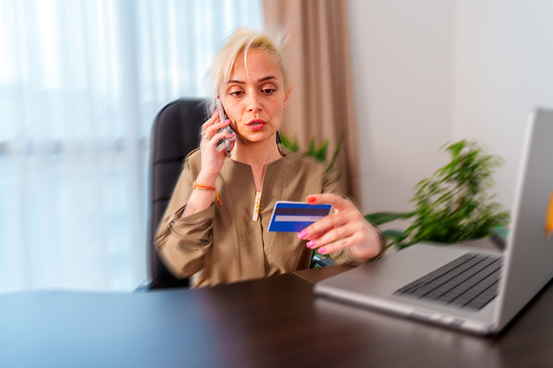 Concerned lady talking on mobile phone having finance stolen from card