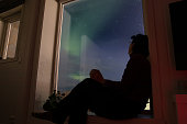 Young woman is watching northern lights at home.