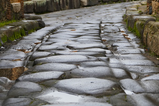 Cobbled streets of the city of Pompeii. Wet streets and cloudy skies. Ancient Roman city buried after the eruption of the Vesuvius volcano in 79AD