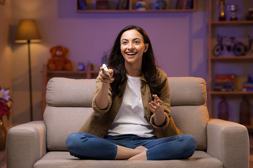 Smiling girl relax on couch turn on air conditioner